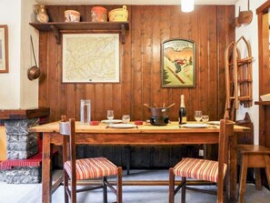 A wooden dining table with chairs, a map, and a poster on the wall.