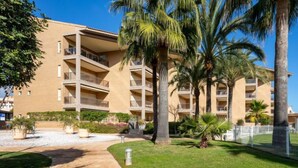 A multi-story hotel with balconies, palm trees, and a paved walkway.