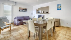 A modern living room with a dining table, chairs, a sofa, and a TV. - Platja de Roses by Interhome (Roses)