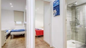 A hotel room with a bed, a small desk, a shower area, and a painting on the wall. - Platja de Roses by Interhome (Roses)