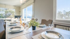 A dining area with a long table set for a meal, large windows, and a view of the outdoors. - Vacation home Gisèle by Interhome (Saint Aygulf)