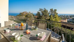 A balcony with a table set for dining, overlooking a scenic view of the sea and surrounding landscape. - Vacation home Gisèle by Interhome (Saint Aygulf)