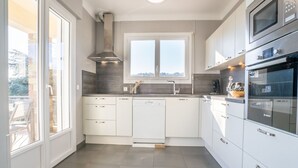 A modern kitchen with white cabinets, a Bosch oven, and a window overlooking a balcony. - Vacation home Gisèle by Interhome (Saint Aygulf)