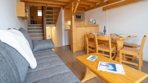 A cozy cabin interior with a wooden staircase, a dining area, and a living room with a sofa. - Brelin Danchet 1026 by Interhome (Les Menuires)