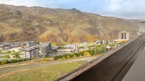 A mountainous landscape with a town featuring modern buildings and a prominent tower. - Brelin Danchet 1026 by Interhome (Les Menuires)