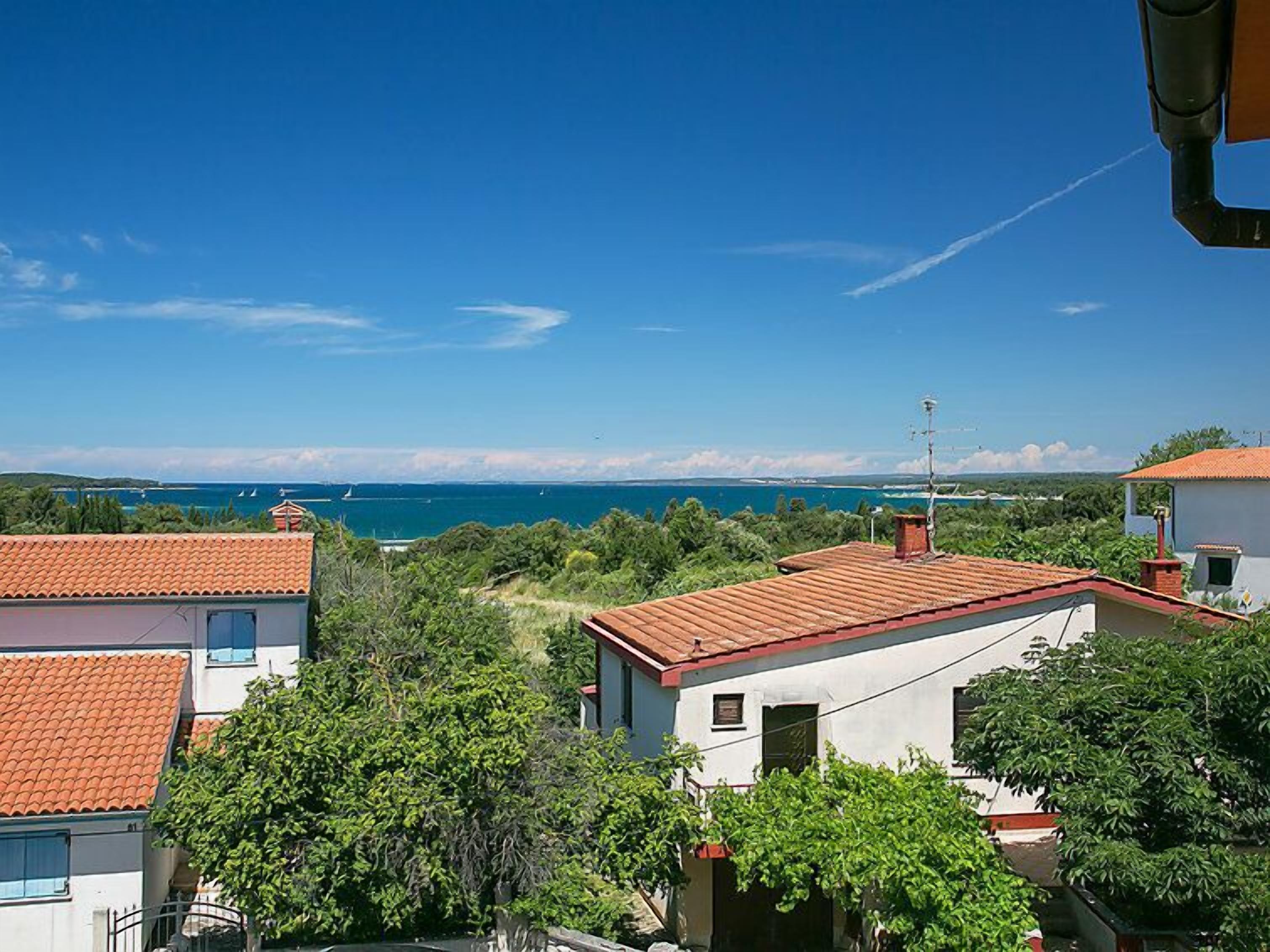 A coastal residential area with houses featuring red-tiled roofs and white walls.