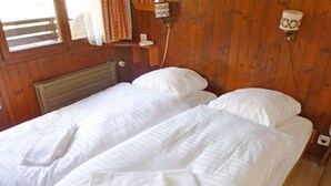Ein Zimmer mit Holzwänden und zwei Einzelbetten, jeweils mit weißen Laken und Handtüchern.