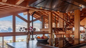 Una cocina moderna con una isla grande, vigas de madera y vistas al cielo.