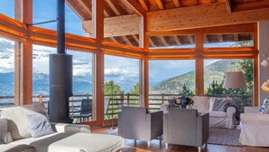 Un salón espacioso con una chimenea grande, asientos cómodos y vistas a las montañas.