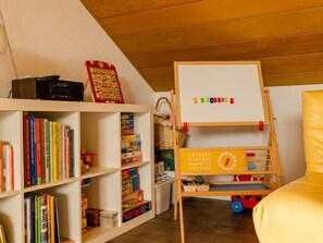 A room with a whiteboard displaying numbers, a bookshelf with books, and a wooden toy structure. - Vacation home Quelle by Interhome (Dittishausen)