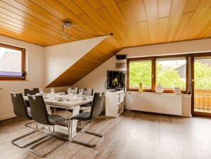 A dining area with a wooden ceiling, a table set for four, and a view of greenery outside. - Vacation home Quelle by Interhome (Dittishausen)