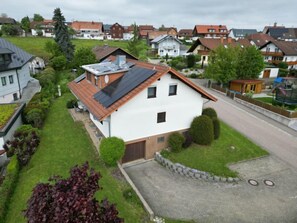 A residential house with a sloped roof, solar panels, and a well-maintained lawn.