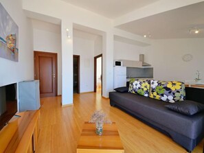 Uma sala de estar moderna com sofá, mesa de centro e área de cozinha ao fundo.