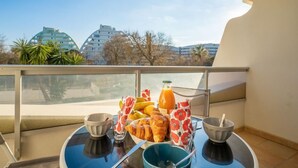 A balcony with a table set for breakfast, including croissants, a bottle of orange juice, and a basket of fruit. - du Parc I by Interhome (La Grande Motte)