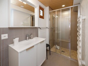 A bathroom with a white sink, mirror, and shower enclosure.