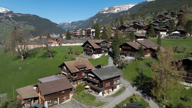 A mountain village with traditional wooden houses, a central square, and a view of snow-capped mountains. - Chalet Almisräba by Interhome (Grindelwald)