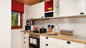 A modern kitchen with white cabinets, a wooden countertop, a stainless steel oven, and a red window blind. - Chalet Almisräba by Interhome (Grindelwald)