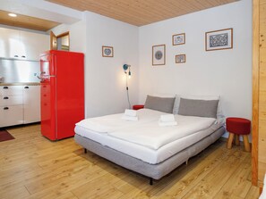 Een slaapkamer met een bed, een rode koelkast en een kitchenette.