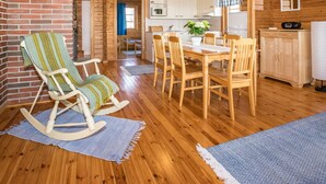 Una cabaña de madera acogedora con comedor, cocina y una mecedora.