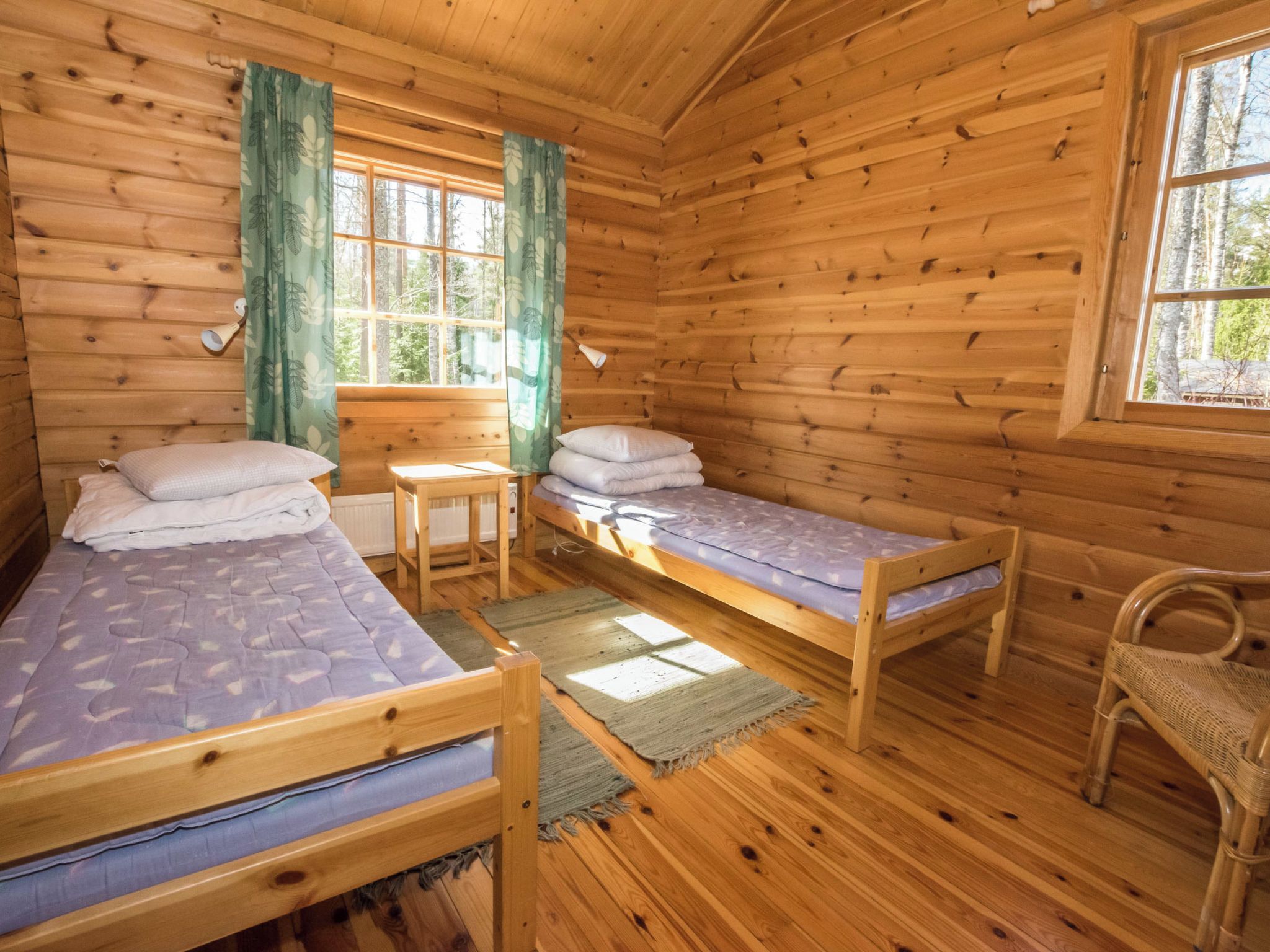 Una cabaña de madera con dos camas individuales, una mesita y una silla.