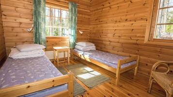 Una cabaña de madera con dos camas individuales, una mesita y una silla.