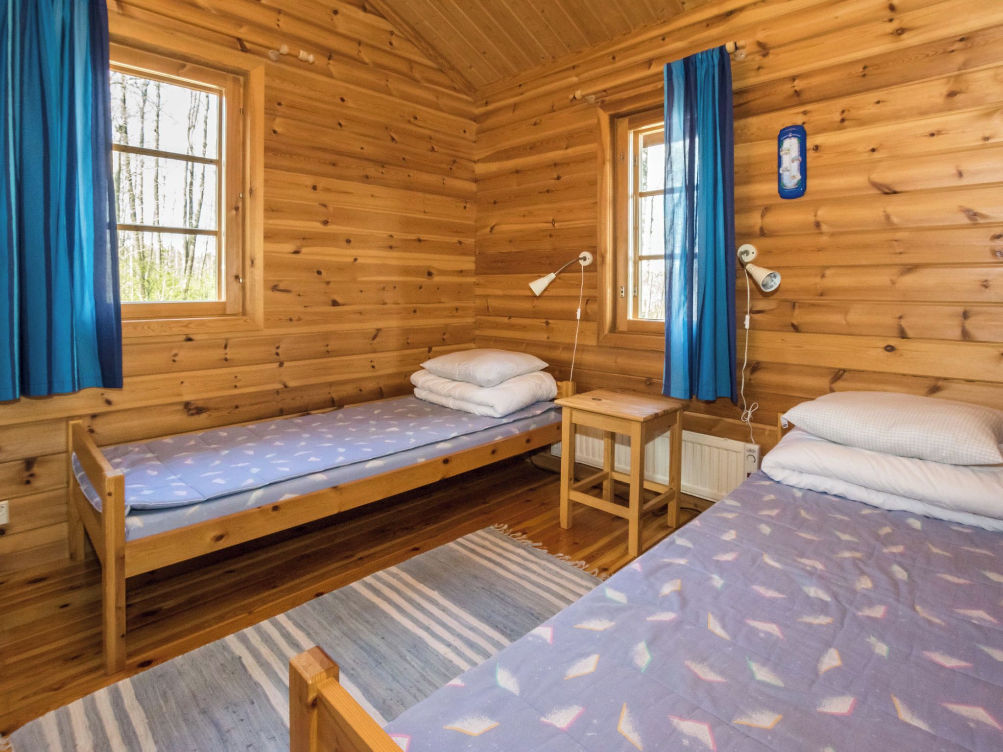 A cabin with two wooden beds, a small table, and a window with curtains.
