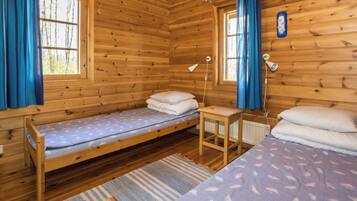 A cabin with two wooden beds, a small table, and a window with curtains.