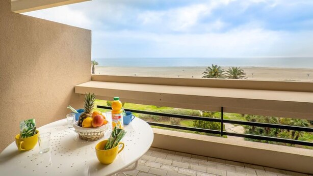 A balcony with a table set for breakfast, overlooking a beach. - Les Terrasses du Levant by Interhome (Canet-Plage)