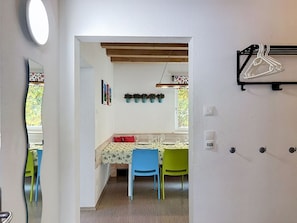 Un comedor con una mesa dispuesta para cuatro, sillas y una planta colgante.