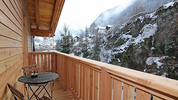 A wooden balcony with a table and chairs, overlooking a snowy mountain landscape. - am Arlberg by Interhome (Pettneu am Arlberg)