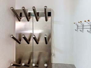 Un refrigerador de acero inoxidable con múltiples compartimentos para botellas y un sistema de ganchos montados en la pared.