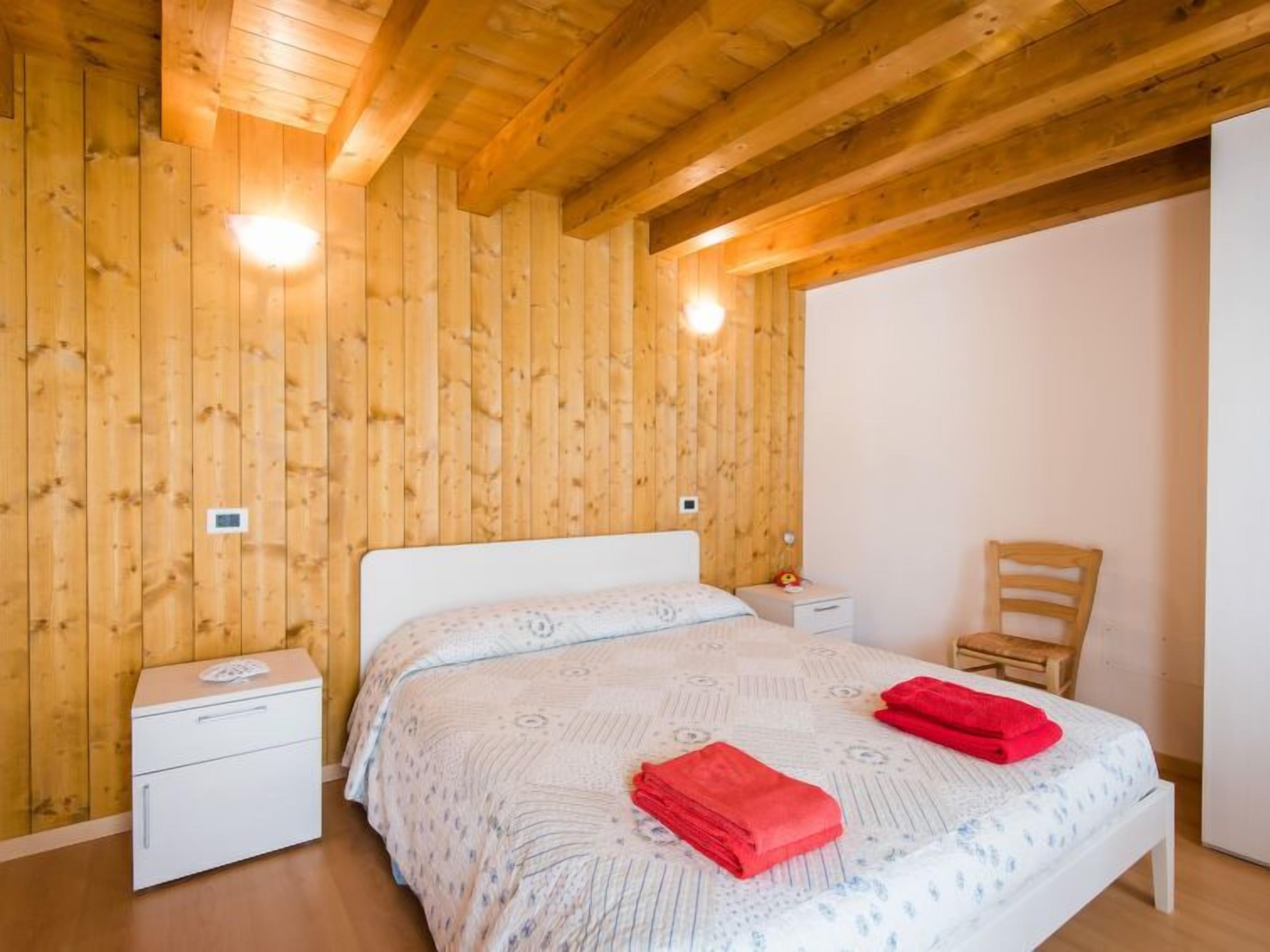 A wooden-paneled bedroom with a bed, nightstands, and a chair.
