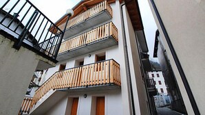 A multi-story building with balconies, a staircase, and a narrow alleyway. - Albergo Diffuso - Cjasa Paron Cilli by Interhome (Barcis Lake)