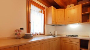A kitchen with wooden cabinets, a sink, and a stove. - Albergo Diffuso - Cjasa Paron Cilli by Interhome (Barcis Lake)
