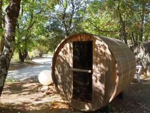 A wooden cylindrical structure with a door, surrounded by trees and a paved path. - La Colline des Ocres by Interhome (Apt)