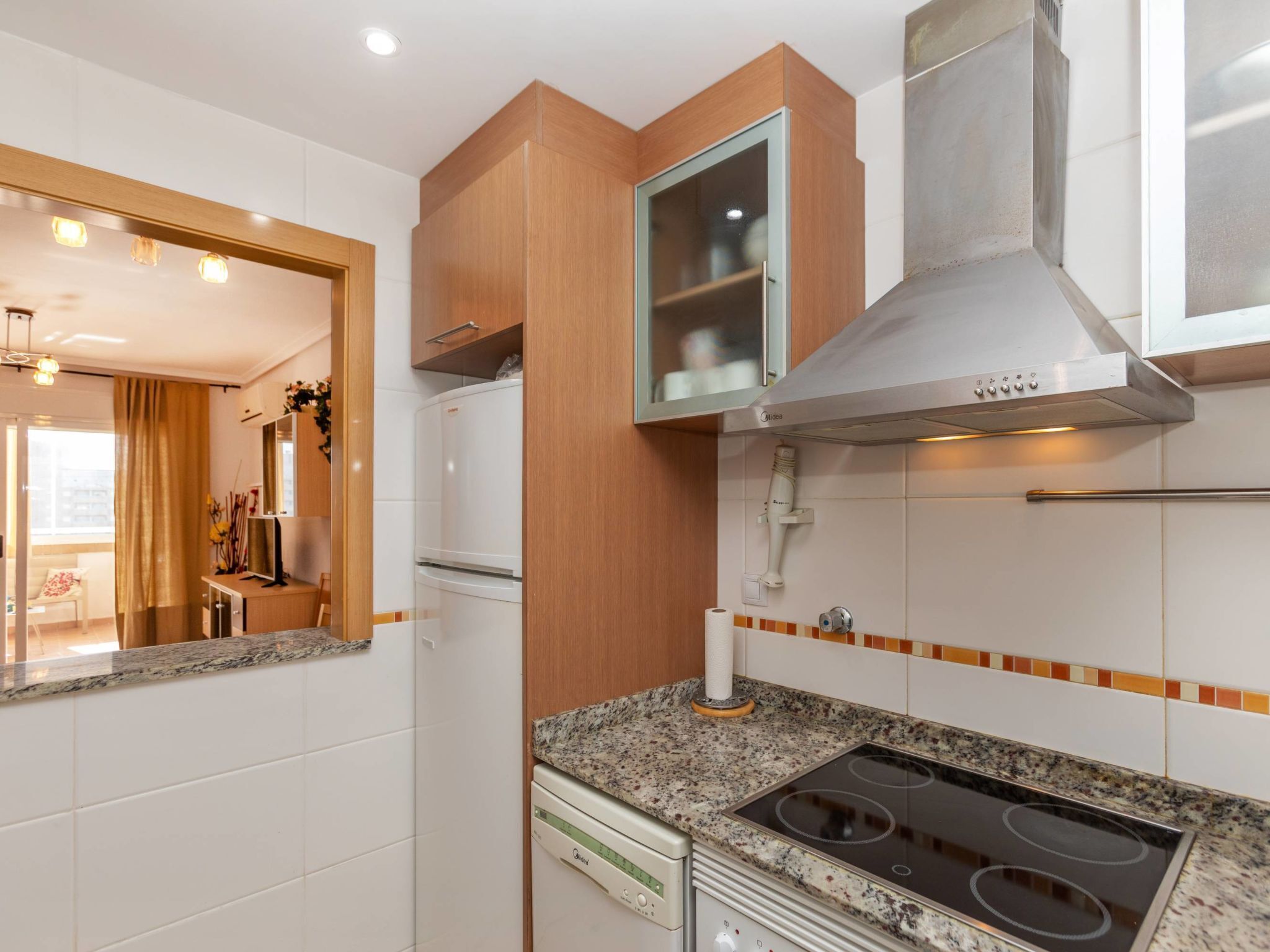 A modern kitchen with a built-in oven, a stainless steel range hood, and a granite countertop.
