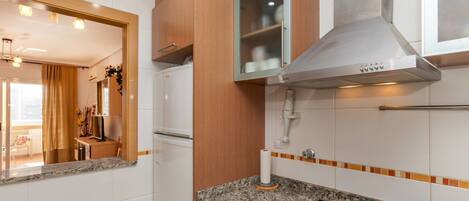 A modern kitchen with a built-in oven, a stainless steel range hood, and a granite countertop.