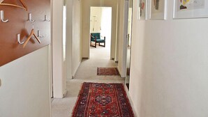 A hallway with a wooden coat rack, a patterned rug, and framed artwork on the walls. - Residenza Corallo by Interhome (Ascona)