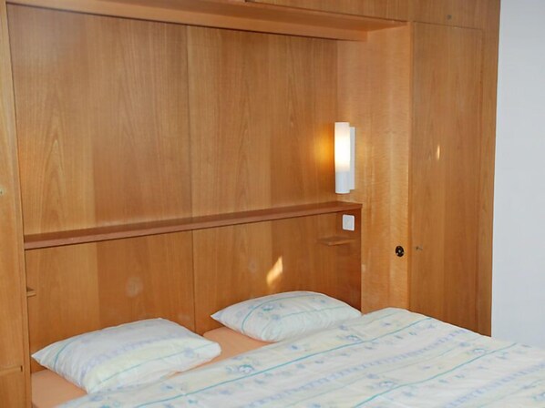 A wooden bunk bed with a headboard and a bedside table.