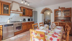Une cuisine dotée de meubles en bois, d’une cuisinière à gaz, d’un four à micro-ondes et d’un coin repas avec une table dressée pour quatre personnes.