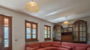 Un salon doté d’un grand canapé d’angle, de meubles en bois et de deux lampes suspendues.