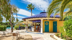 A covered outdoor seating area with tables and chairs, a kiosk, and a building with a blue roof. - Les Rivages des Issambres by Interhome (Les Issambres)
