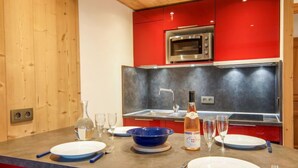 Une cuisine moderne avec des meubles rouges, un four encastré et un plan de travail en granit.