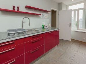 A kitchen with red cabinets, a stainless steel sink, and a window with a view.