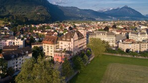 Una città con edifici storici, un ampio campo aperto e montagne sullo sfondo.