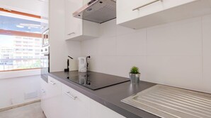 A modern kitchen with white cabinets, a black countertop, and a small potted plant. - Le Méditerranée by Interhome (Fréjus)