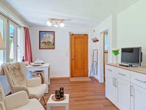 Een moderne kamer met een eettafel, stoelen, een televisie en een schilderij aan de muur.