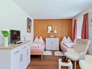 A compact room with a bed, a desk, a chair, and a television.