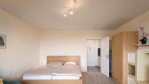 Ein modernes Schlafzimmer mit einem hölzernen Bett, einem grünen Sofa, einem weißen Nachttisch und einem Holzschrank.