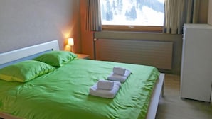 Ein Hotelzimmer mit einem Bett, einem Nachttisch mit Lampe, einem Fenster mit Vorhängen und einer Heizung.